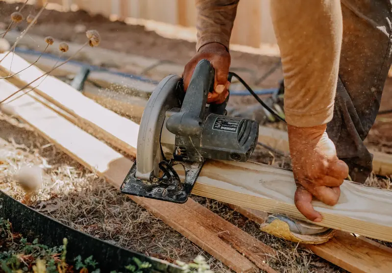 Hands cutting a timber board with a circular saw